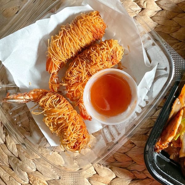 Three crispy fried shrimp with noodle-like coating and a side of sweet chili sauce in a takeout container.